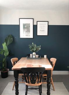 a dining room table with four chairs and two pictures on the wall above it, along with potted plants