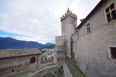 an old stone building with two towers in the middle of it and mountains in the background