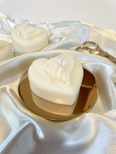 two soaps sitting on top of a gold plate next to a white satin cloth