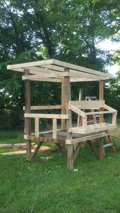 a wooden structure sitting on top of a lush green field next to a park bench