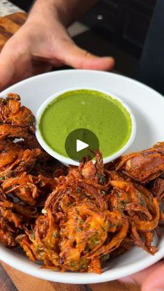 a white plate topped with fried food next to a green sauce