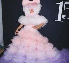 a woman in a pink and purple dress standing on a red carpet with her hands on her hips