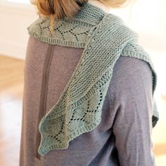 a woman wearing a green knitted scarf on top of her head and back to the camera