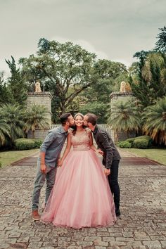 three people standing next to each other on a brick walkway in front of some trees