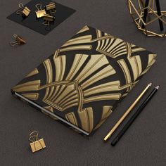 an open notebook with gold art deco design on the cover, surrounded by stationery items