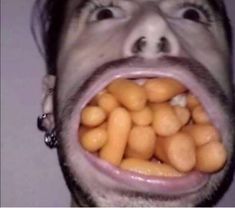 a man with his mouth open and some peanuts coming out of his mouth to eat