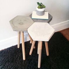 three small tables are stacked on top of each other in front of a white wall