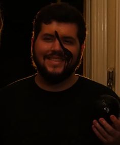 a man with his face painted to look like he is holding a bowling ball and smiling at the camera