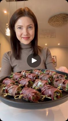 a woman holding a platter full of food