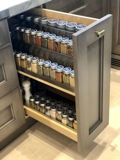 an open cabinet in the middle of a kitchen with spices and seasonings on it