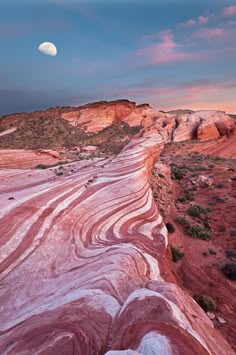 the moon is setting over red rock formations