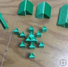 several green origami pieces are arranged on a wooden table with one piece missing