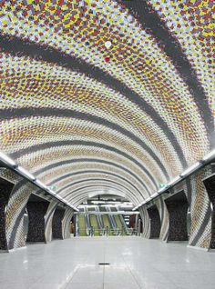 the inside of a subway station with colorful mosaic tiles on the ceiling and tiled floor