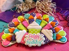 a decorated cookie with happy birthday written on the top and colorful icing around it