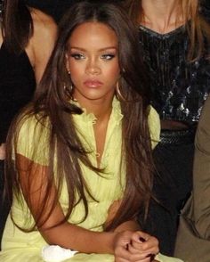 a woman sitting in front of a crowd with her hair blowing back and looking at the camera