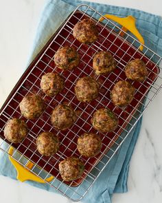 some meatballs are on a wire rack and sitting on a blue towel next to a yellow spatula