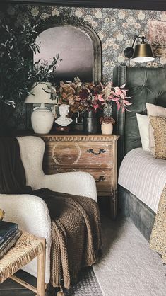 a bedroom with floral wallpaper and an old fashioned dresser next to the bed is decorated with potted plants