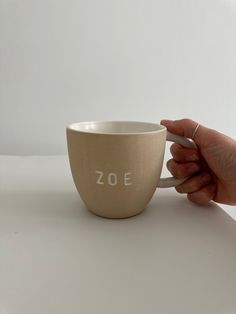 a hand holding a coffee cup with the word zoe written on it