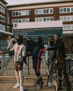 some people are standing near a fence with their arms in the air and one person on a bike