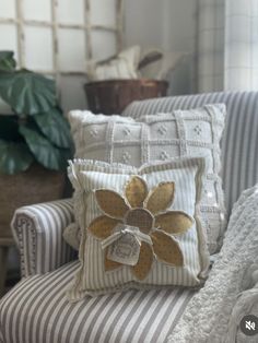 a chair with some pillows on it and a potted plant in the back ground