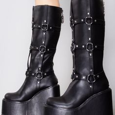 Keep Them In Their Place With The Stomp O-Ring Platform Boots From Yru. These Ultra Sexy Festival Boots Feature An All Black Vegan Leather Upper With Strapped O-Ring Details And Zipper Closure Up The Back. They May Want You, But They’ll Have To Say Please First. "Faf Stomp O-Ring Platform Boots 6"" Heel & 2 3/4"" Platform Vegan Leather Triple O-Ring Strapped Knee High Logo Zipper Pull Black Punk Synthetic Boots For Concerts, Punk Style Platform Boots In Synthetic Material, Alternative Synthetic Boots For Concerts, Alternative Style Synthetic Boots For Concerts, Gothic Boots For Alternative Fashion, Alternative Style Synthetic Boots For Alternative Fashion, Edgy Synthetic Platform Boots, Gothic Synthetic Boots For Concerts, Punk Style Platform Boots In Polyurethane