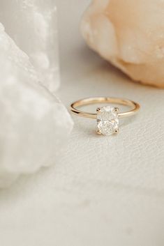 a diamond ring sitting on top of a white table next to a rock and flower