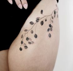 a woman's thigh with small black leaves on the side and one arm behind her