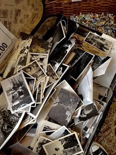 an open suitcase filled with old photos and other things on the floor next to a basket