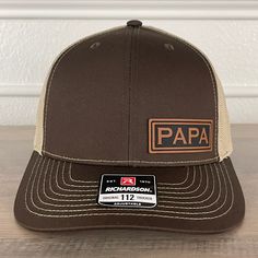 PAPA side leather patch hat Brown/Khaki. Specifications: 🧢 Richardson original 112 trucker; adjustable for the perfect fit 🎩 60/40 cotton/polyester blend for comfort 📏 One size fits most 🏷️ Expertly laser engraved leatherette patch design 📦 Ships in 2 to 3 business days from our Orlando Studio Care Instructions: 🚫 Do not wash; spot clean only Please Note: 🌈 Colors may vary from photos based on your viewing screen. Brown Flat Bill Baseball Cap For Outdoor, Outdoor Brown Hats With Leather Backing, Brown Hats With Leather Backing For Outdoor, Outdoor Brown Hat With Leather Backing, Brown Hat With Leather Backing For Outdoor, Adjustable Leather Snapback Hat In Brown, Brown Leather Snapback Hat, Adjustable Leather Brown Snapback Hat, Adjustable Brown Leather Snapback Hat