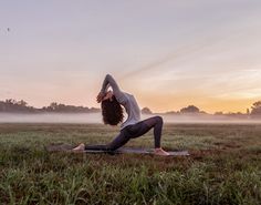 a woman doing yoga in the middle of a field with foggy sky behind her