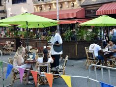 people are sitting at tables with umbrellas over them