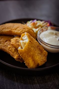 fried fish and coleslaw on a black plate