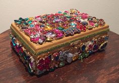 a wooden table topped with a colorful jeweled box