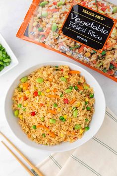 a white bowl filled with rice and vegetables next to a bag of veggie fried rice