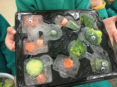 a person holding an ice tray filled with frozen vegetables