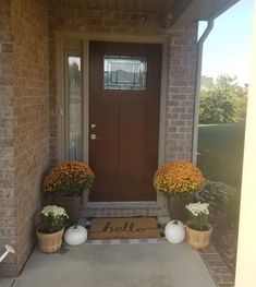 the front door is decorated with pumpkins and flowers