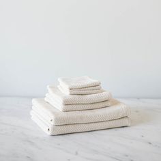 six white towels stacked on top of each other in front of a white wall and floor