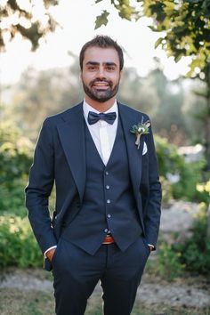 a man in a tuxedo poses for the camera with his hands in his pockets