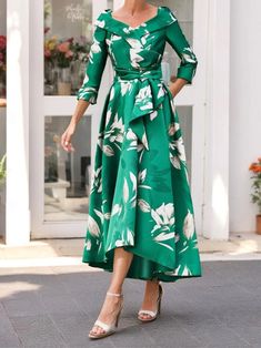 a woman in a green dress is walking down the street with her hands on her hips