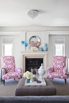 a living room filled with furniture and a fire place under a chandelier in front of a fireplace