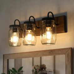 three mason jar lights are hanging on the wall next to a mirror and framed by a wooden frame