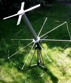 a white wind turbine sitting on top of a lush green field