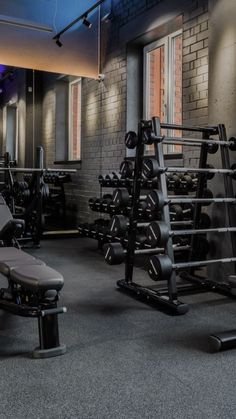 a gym with rows of exercise equipment and blue lights on the ceiling in front of windows