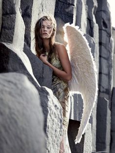 a woman with an angel wings standing in front of some rocks