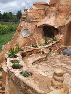 an unusual house built into the side of a hill with plants growing out of it