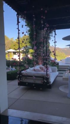 a woman laying on top of a white couch next to a lush green forest covered in pink flowers