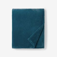 a teal blanket folded on top of a white wall