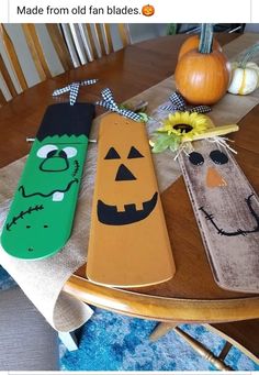 three wooden spoons decorated to look like halloween characters on a table with pumpkins in the background