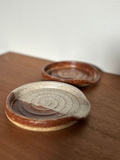 two brown and white bowls sitting on top of a wooden table