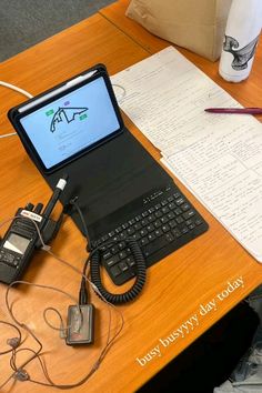 an open laptop computer sitting on top of a wooden desk next to a cell phone